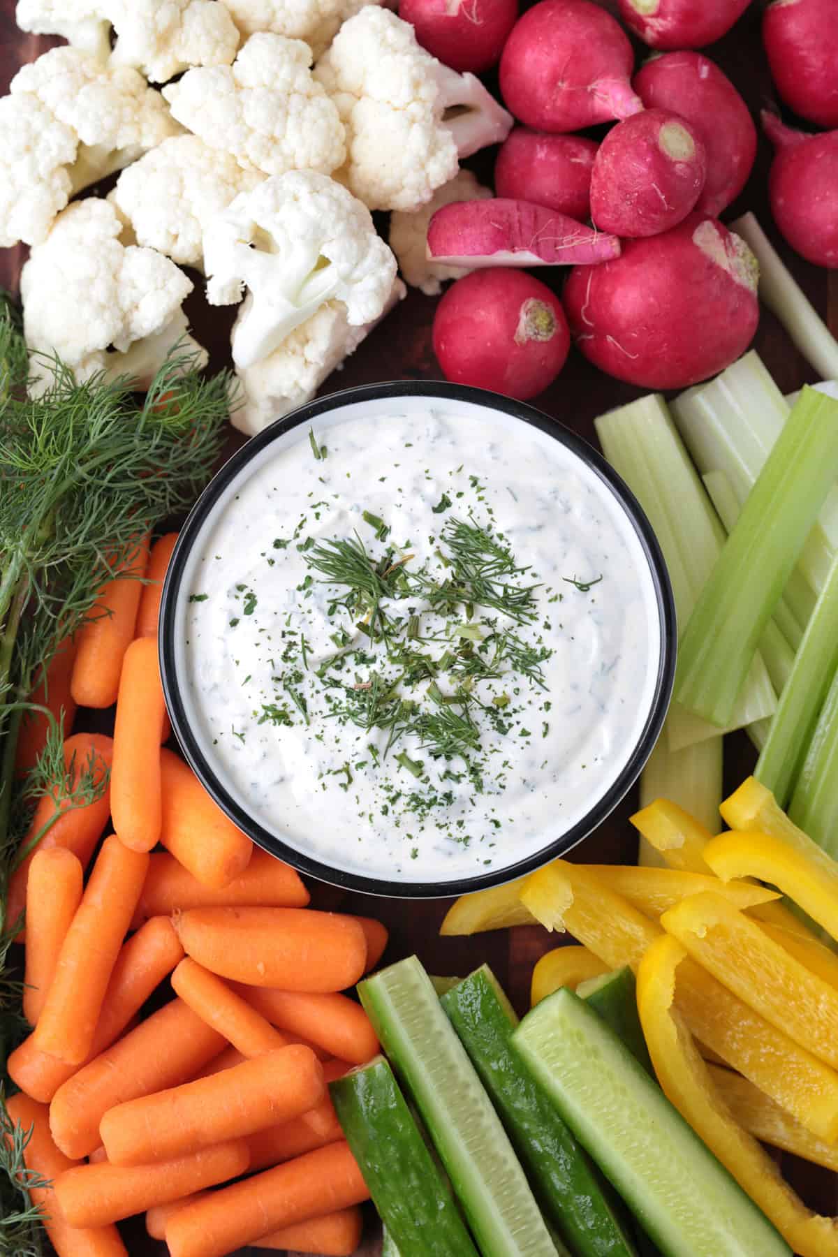 One taste of our Homemade Ranch Dip and you won't go back to store bought! Just five minutes to make – it's fresh and herby and so addicting. board with homemade ranch in a bowl surrounded with vegetables