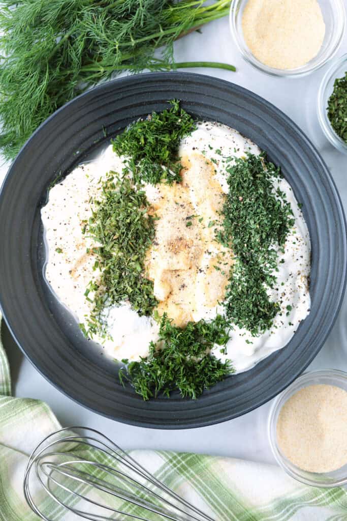 One taste of our Homemade Ranch Dip and you won't go back to store bought! Just five minutes to make – it's fresh and herby and so addicting. process picture of ingredients for ranch dip in a bowl