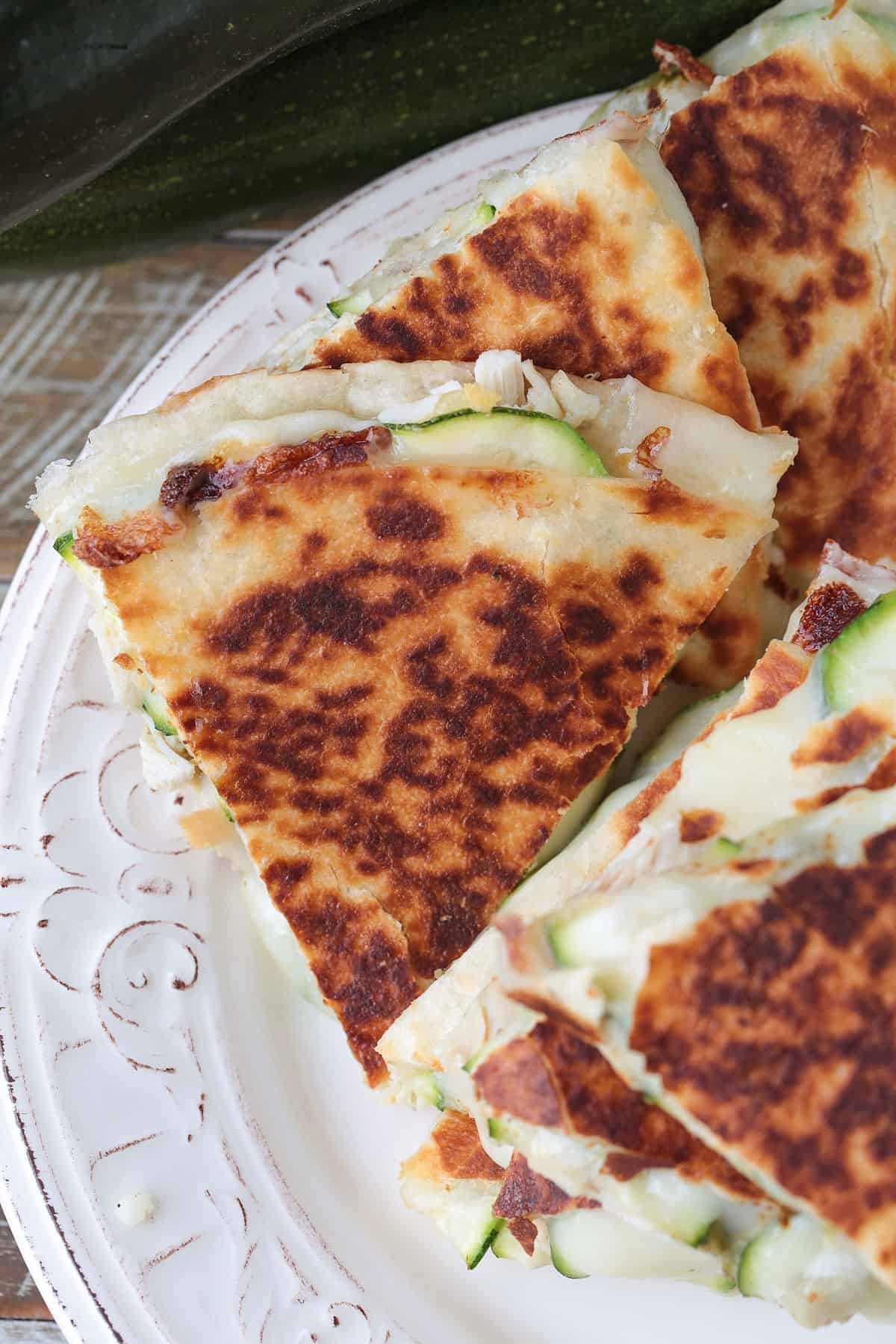 Crispy Chicken Zucchini Quesadillas are filled with tender chicken, thinly sliced zucchini and gooey cheese for an easy 30 minute dinner. chicken and zucchini quesadillas cut and stacked on a plate