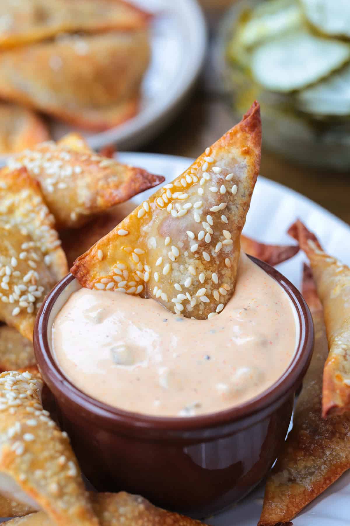 Cheeseburger Wontons are sure to become a new favorite! A beefy, cheesy filling stuffed into crispy wontons and dipped in our big mac sauce! cheeseburger wonton dipping into big mac sauce