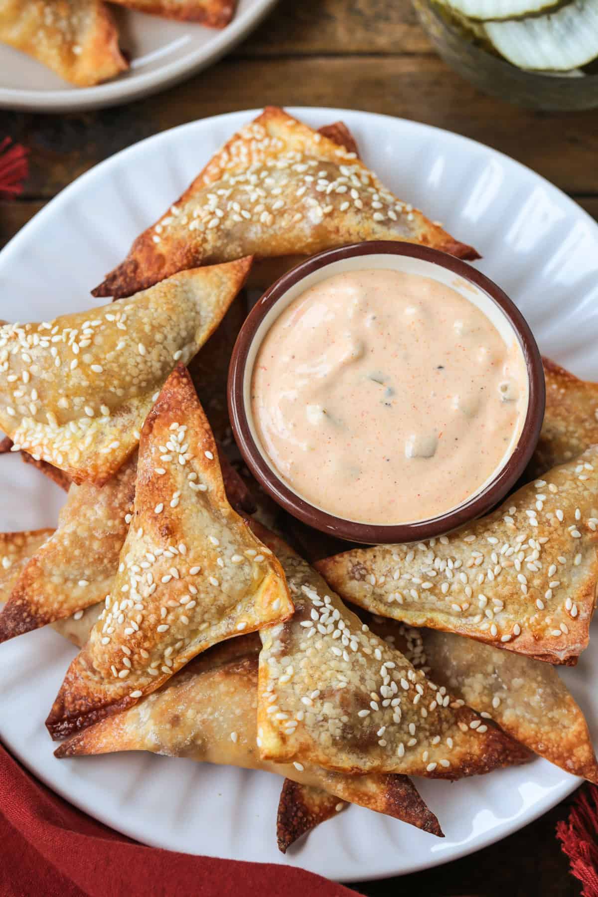 Cheeseburger Wontons are sure to become a new favorite! A beefy, cheesy filling stuffed into crispy wontons and dipped in our big mac sauce! cheeseburger wontons with sesame seeds on a plate with sauce
