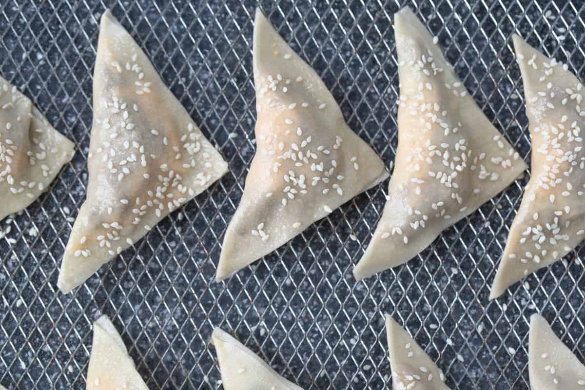 Cheeseburger Wontons are sure to become a new favorite! A beefy, cheesy filling stuffed into crispy wontons and dipped in our big mac sauce! wontons with sesame seeds in an air fryer basket