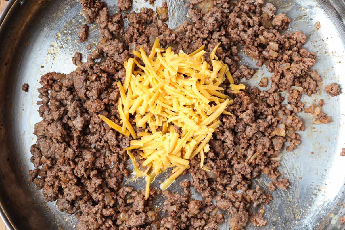 Cheeseburger Wontons are sure to become a new favorite! A beefy, cheesy filling stuffed into crispy wontons and dipped in our big mac sauce! cooked ground beef in a skillet with shredded cheese
