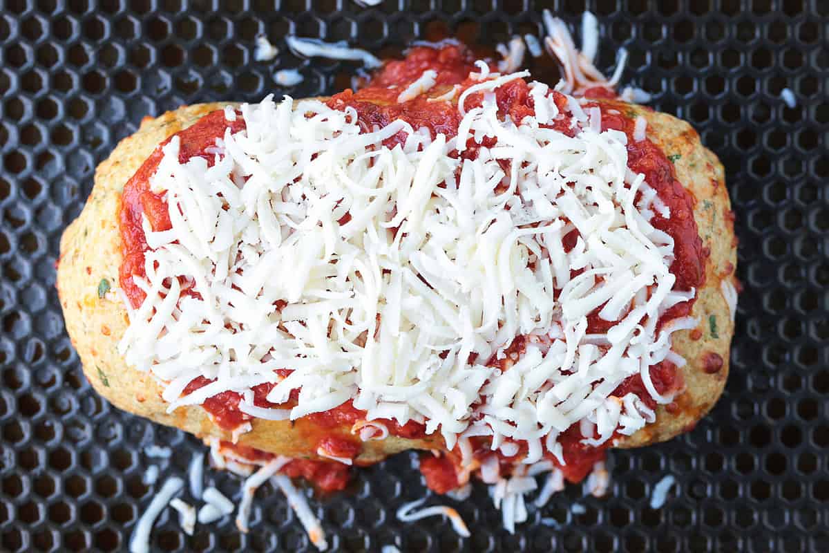 Chicken Parmesan Meatloaf has all the flavors of the classic dish. Juicy and flavorful meatloaf smothered with sauce and mozzarella cheese! meatloaf topped with sauce and cheese on baking sheet
