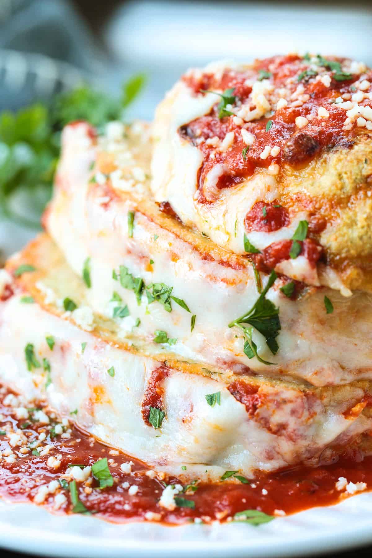 Chicken Parmesan Meatloaf has all the flavors of the classic dish. Juicy and flavorful meatloaf smothered with sauce and mozzarella cheese! chicke parmesan meatloaf sliced and stacked on a white plate