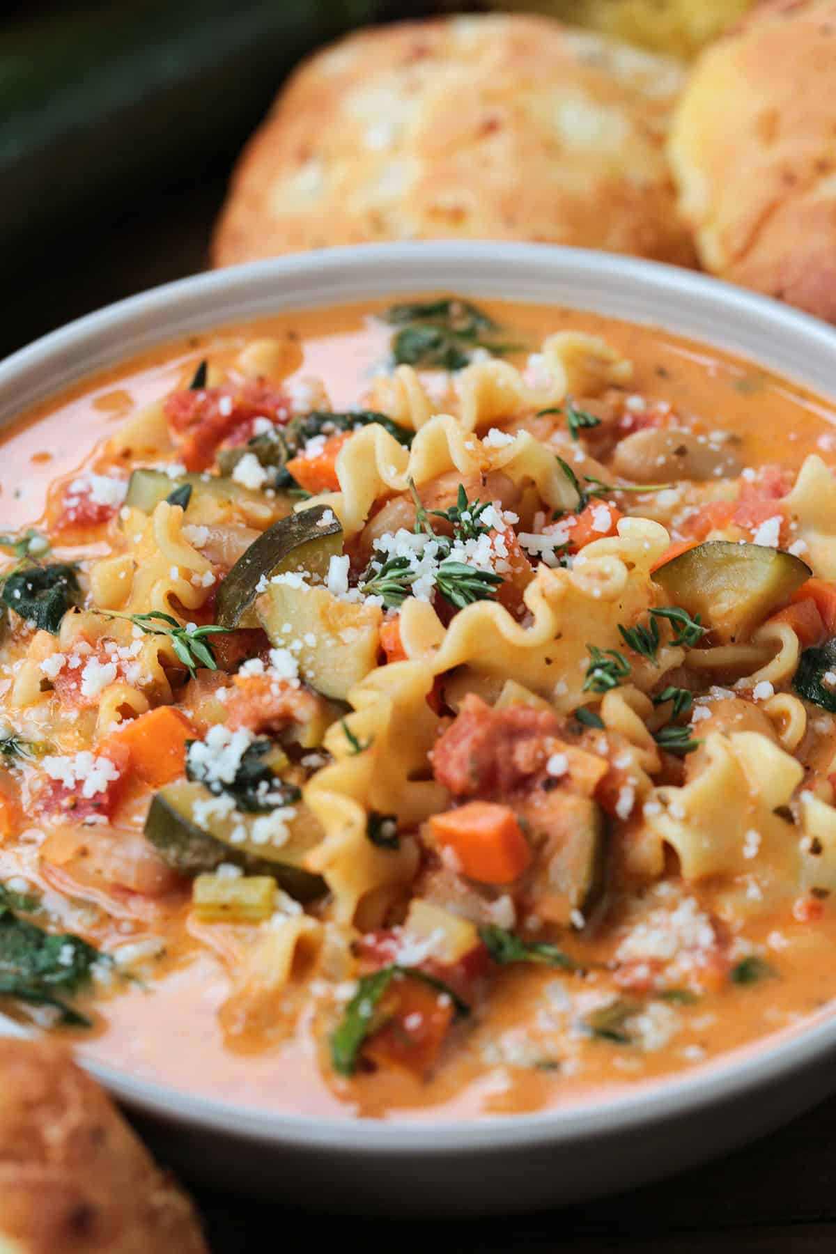 minestrone soup in a bowl from the side with rolls