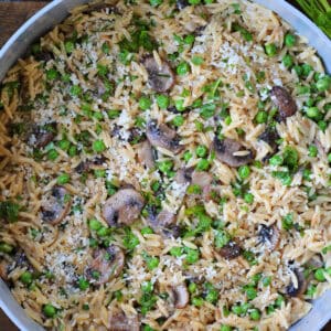 mushroom and pea orzo in a pot with parmesan cheese and parsley on the side
