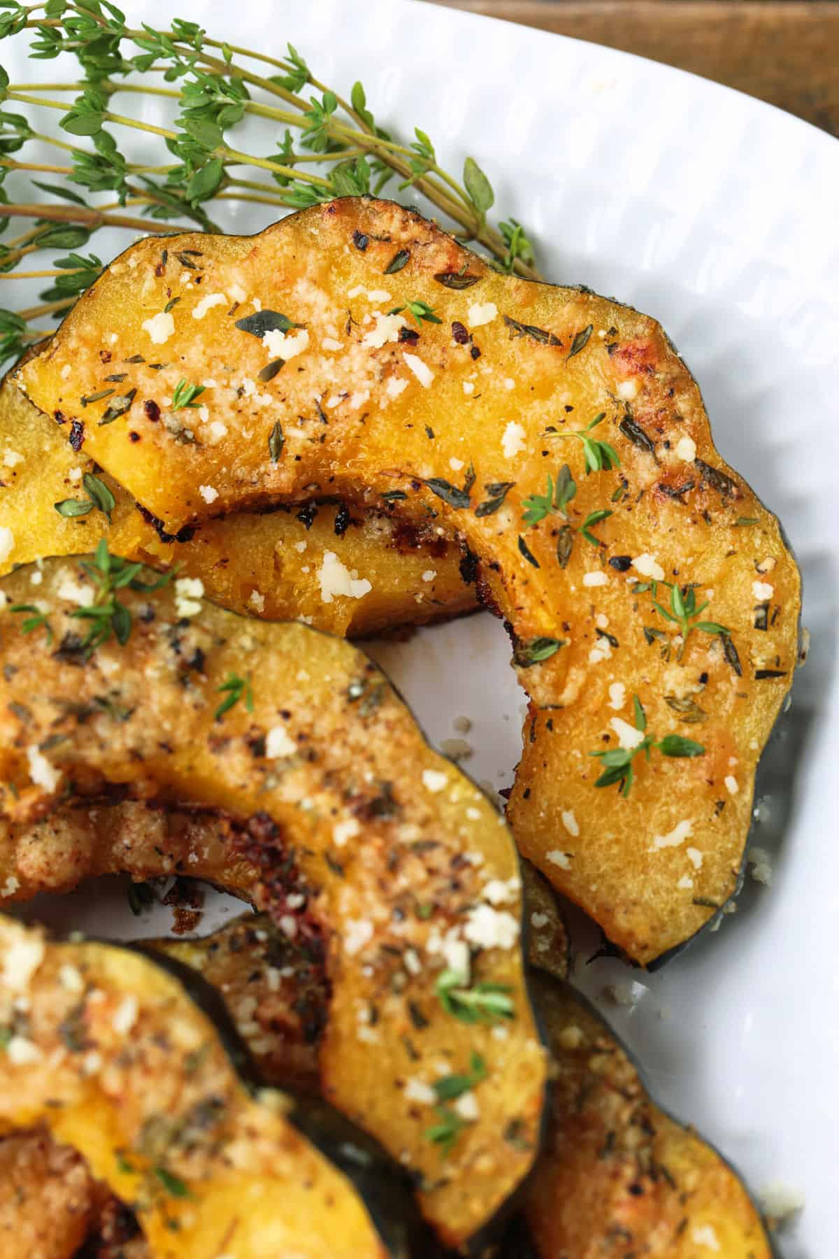 Roasted Parmesan Acorn Squash is so easy to make! Nutty parmesan cheese with fresh thyme is hands down a winning flavor combination. acorn squash sliced and roasted on a platter
